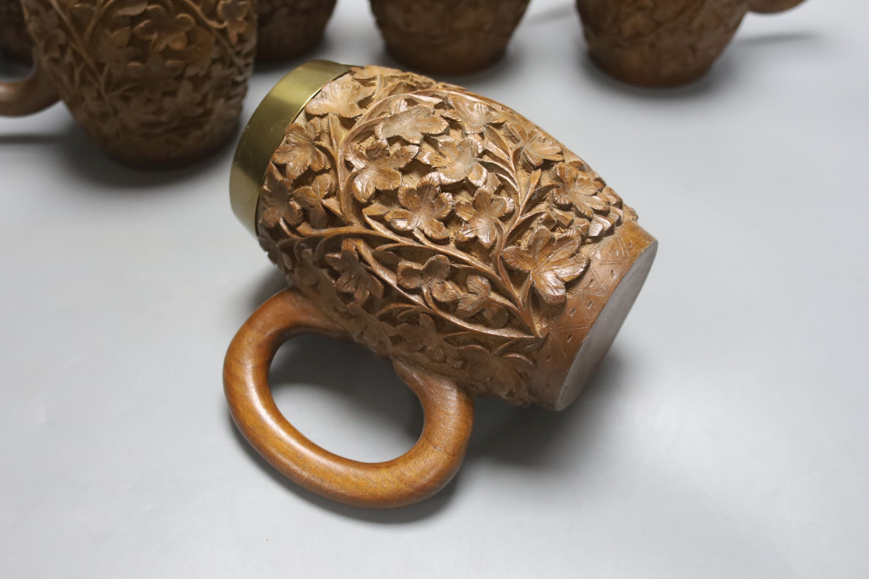 A set of six South Asian carved teak mugs 15.5cm